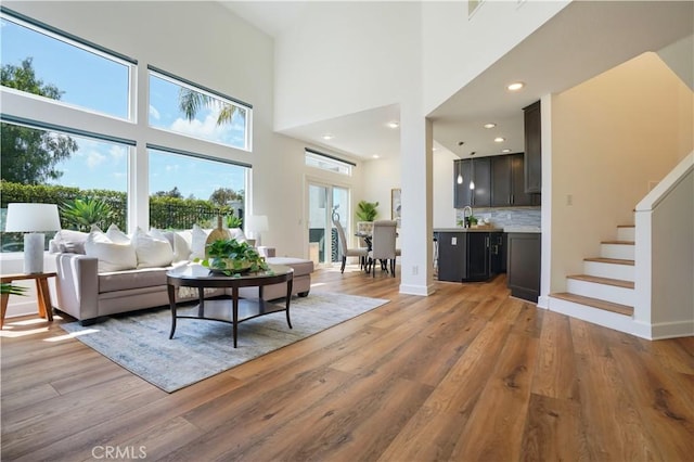 living room with light wood finished floors, stairway, a high ceiling, and recessed lighting