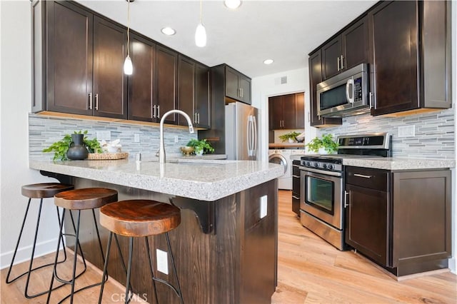 kitchen featuring a peninsula, dark brown cabinetry, stainless steel appliances, and a sink
