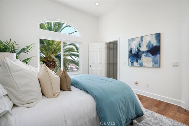 bedroom with recessed lighting, baseboards, a high ceiling, and dark wood-style floors