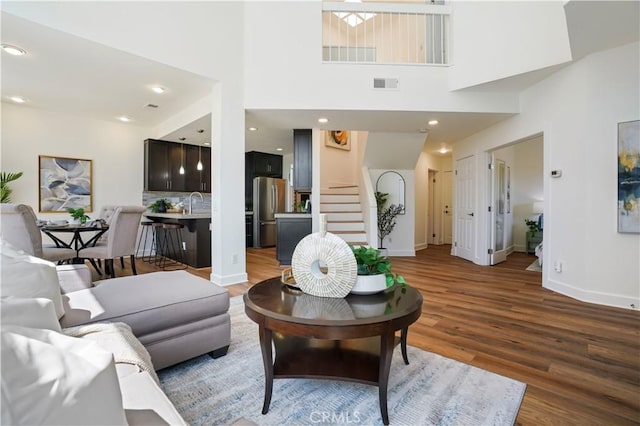 living area featuring stairway, baseboards, visible vents, and wood finished floors