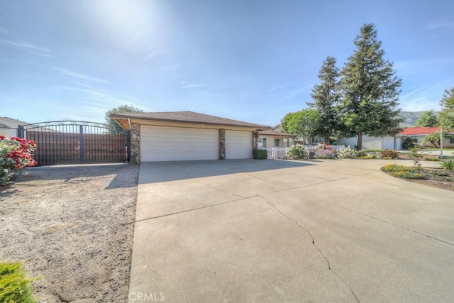 view of front of home with stone siding, a gate, a garage, fence, and concrete driveway