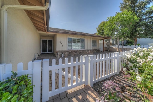 view of front of property featuring stone siding, a fenced front yard, a gate, and board and batten siding