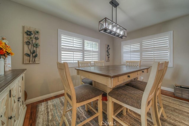 dining area featuring an inviting chandelier, baseboards, and wood finished floors