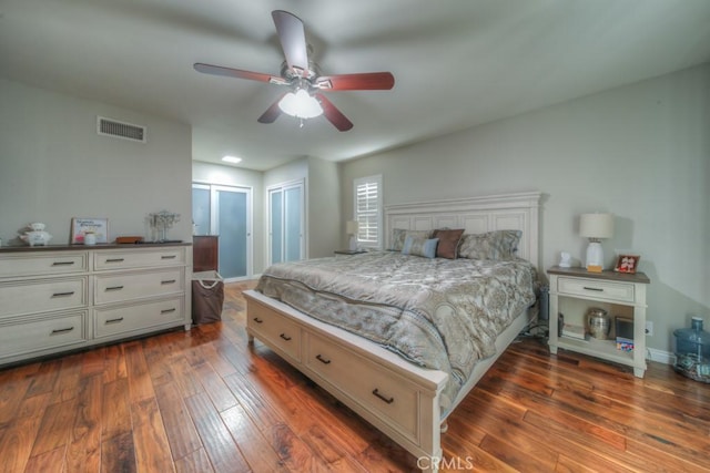 bedroom with ceiling fan, baseboards, dark wood-type flooring, and visible vents