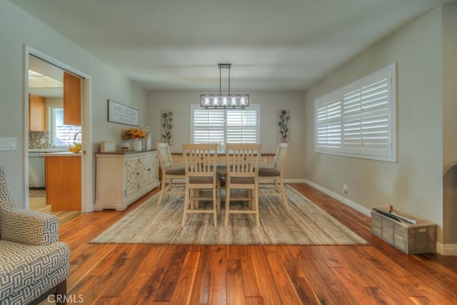 dining area featuring a chandelier, baseboards, and light wood-style floors