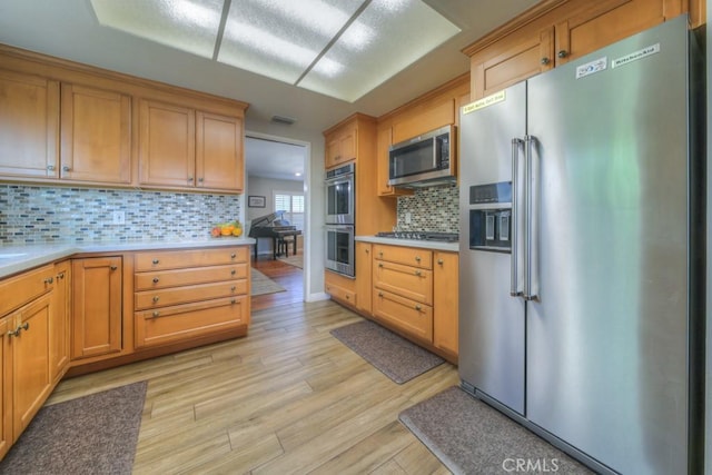 kitchen featuring backsplash, light wood-style floors, stainless steel appliances, and light countertops
