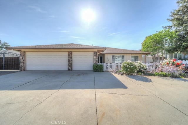 ranch-style home featuring driveway, an attached garage, fence private yard, stone siding, and a gate