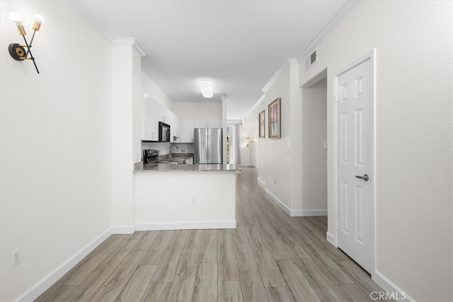 interior space featuring visible vents, a sink, light wood-style flooring, and baseboards