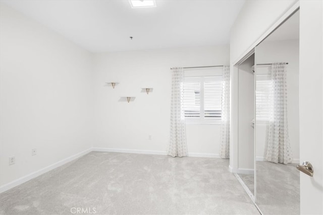 unfurnished bedroom featuring baseboards, light carpet, and a closet