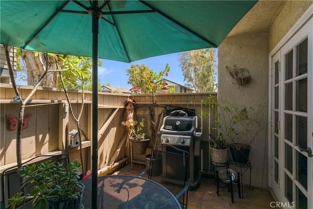 view of patio with a grill, fence, and outdoor dining space