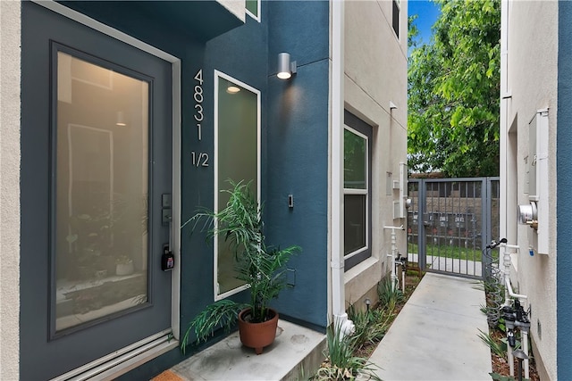 view of exterior entry featuring a gate and stucco siding