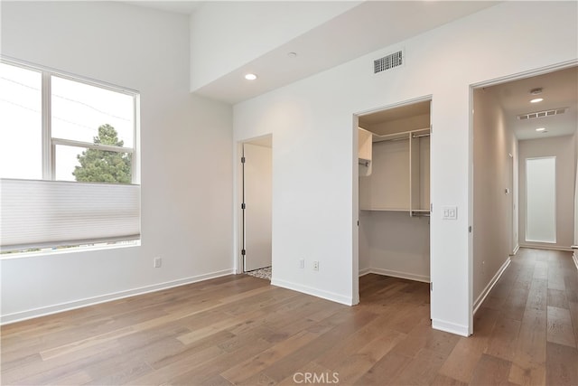 unfurnished bedroom with visible vents, wood-type flooring, and baseboards