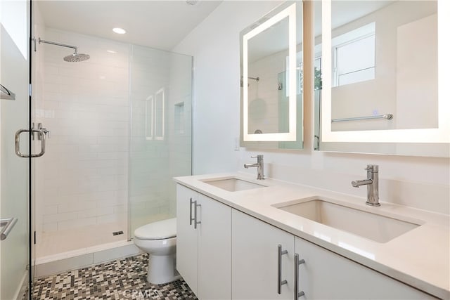 bathroom with a sink, a stall shower, toilet, and double vanity