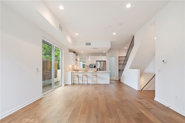 unfurnished living room featuring light wood-style floors, baseboards, and visible vents