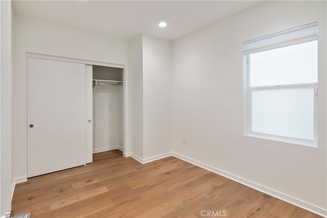 unfurnished bedroom featuring a closet, baseboards, recessed lighting, and light wood-type flooring