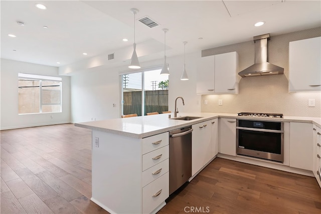 kitchen featuring visible vents, a healthy amount of sunlight, wall chimney exhaust hood, a sink, and appliances with stainless steel finishes