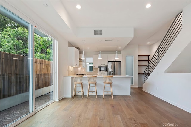 kitchen featuring appliances with stainless steel finishes, light wood finished floors, light countertops, white cabinetry, and visible vents