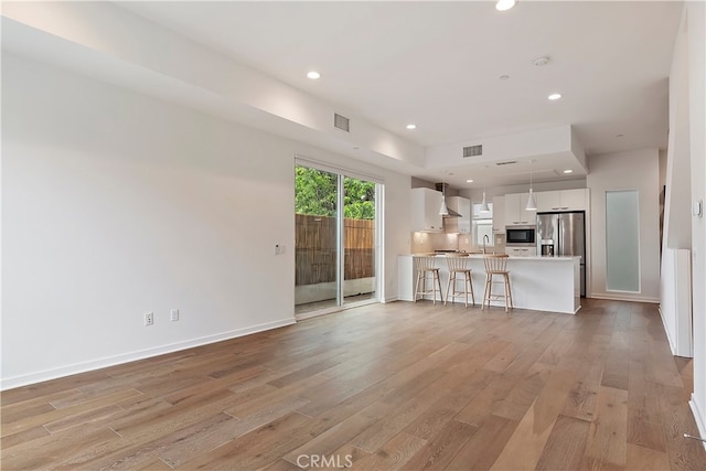 unfurnished living room with visible vents, a sink, light wood finished floors, and recessed lighting