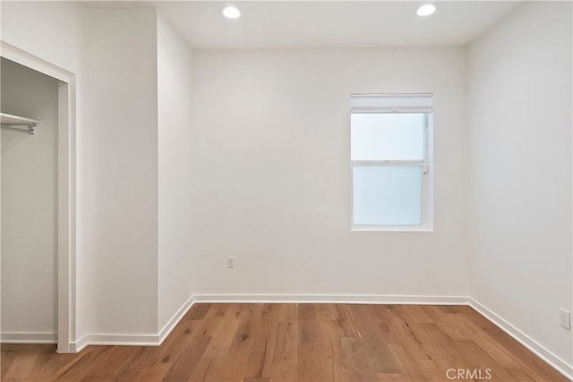 unfurnished bedroom with baseboards, a closet, recessed lighting, and wood finished floors