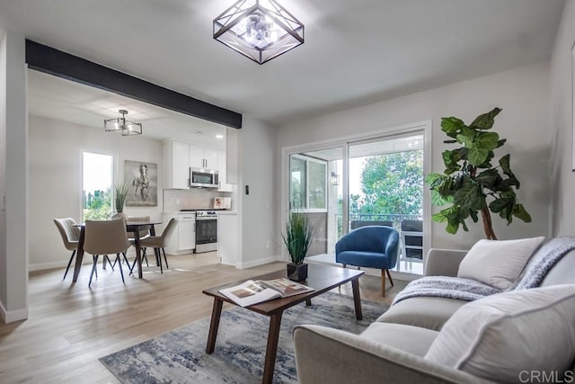 living area with an inviting chandelier, baseboards, and light wood finished floors