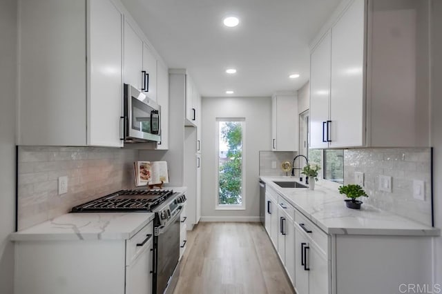 kitchen with light stone countertops, light wood-type flooring, recessed lighting, a sink, and stainless steel appliances