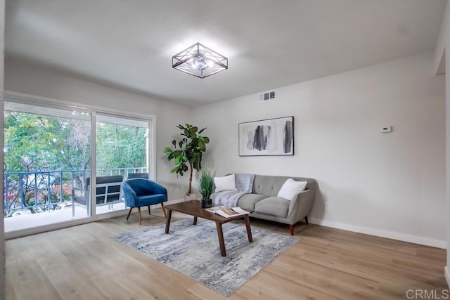 living room featuring visible vents, baseboards, and wood finished floors