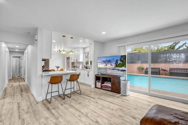 8394 Blue Lake Dr, San Diego, CA 92119 - kitchen featuring a breakfast bar area, light countertops, white cabinets, a peninsula, and light wood-style flooring