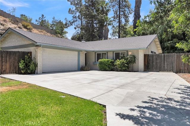 ranch-style house with a garage, fence, stucco siding, and driveway