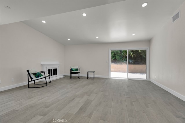 unfurnished room with visible vents, baseboards, light wood-type flooring, a fireplace with raised hearth, and recessed lighting