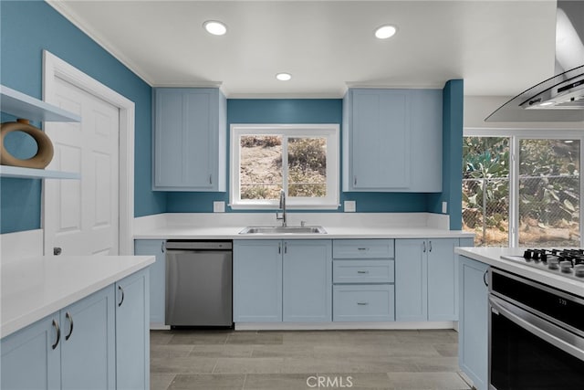kitchen with wall chimney range hood, light countertops, a sink, a wealth of natural light, and stainless steel appliances