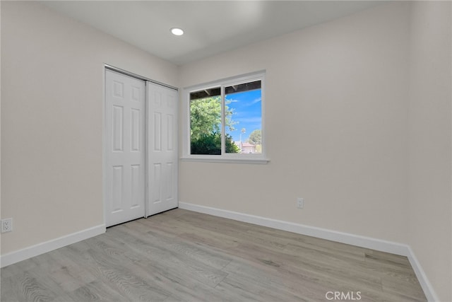 unfurnished bedroom with baseboards, recessed lighting, light wood finished floors, and a closet