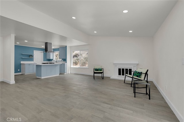 sitting room featuring recessed lighting, light wood-style flooring, and a glass covered fireplace