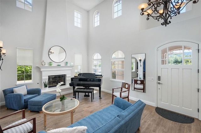 living area featuring baseboards, a high ceiling, wood finished floors, and a notable chandelier