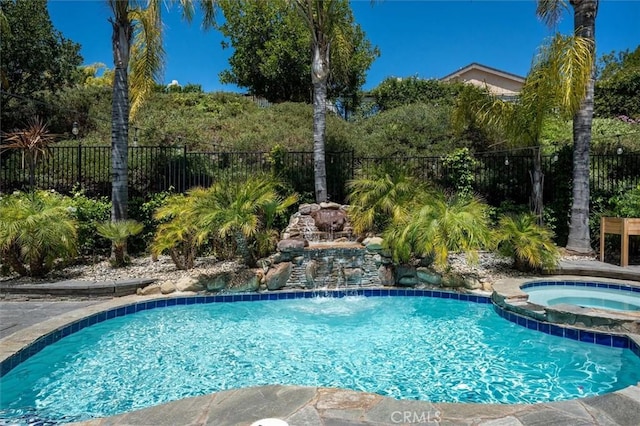 view of swimming pool with fence and a pool with connected hot tub