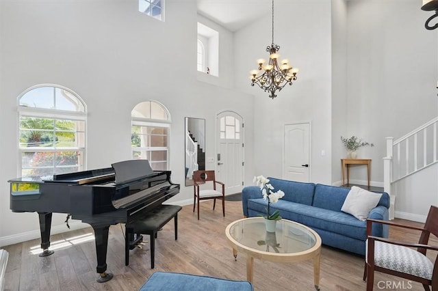 living room with wood finished floors, baseboards, a notable chandelier, a high ceiling, and stairs