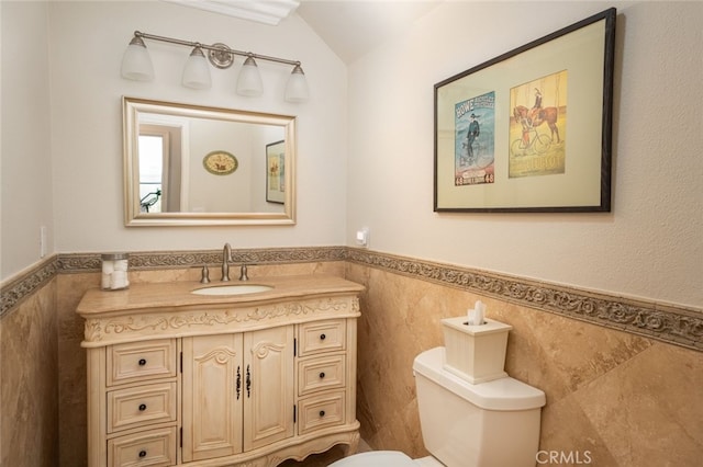 bathroom with a wainscoted wall, toilet, and tile walls