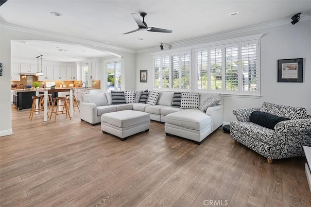 living room featuring crown molding, a ceiling fan, recessed lighting, and light wood-style floors