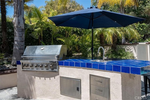 view of patio featuring grilling area, an outdoor kitchen, and a sink