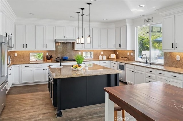 kitchen with a kitchen island with sink, white cabinets, light stone countertops, and a sink