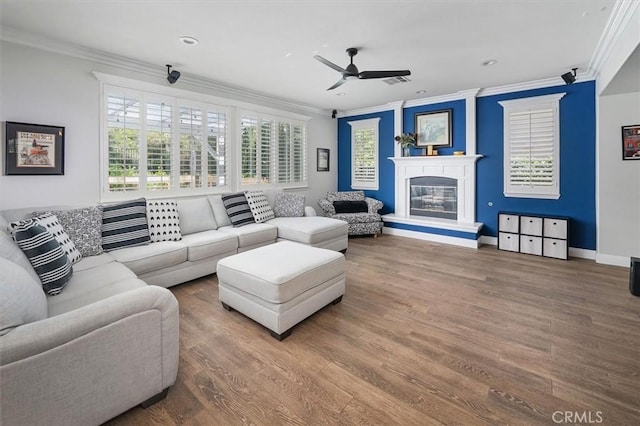 living area with crown molding, a glass covered fireplace, and wood finished floors