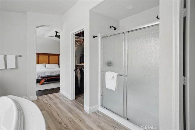 bathroom featuring a garden tub, ceiling fan, a stall shower, and wood finished floors