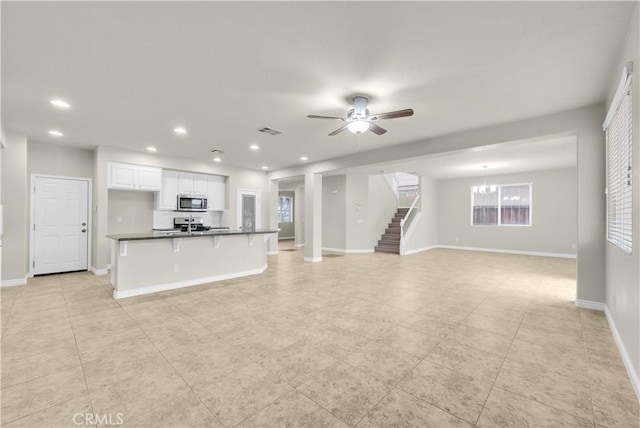 9058 Chimney Rock Ave, Hesperia, CA 92344 - unfurnished living room featuring recessed lighting, baseboards, visible vents, ceiling fan with notable chandelier, and stairs