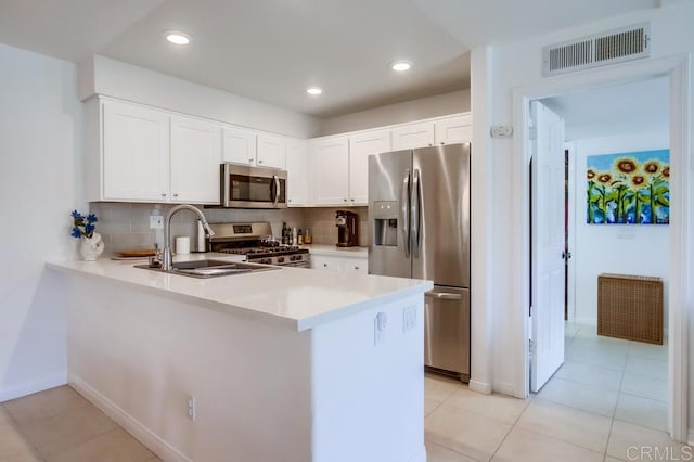 kitchen featuring decorative backsplash, visible vents, a sink, a peninsula, and stainless steel appliances