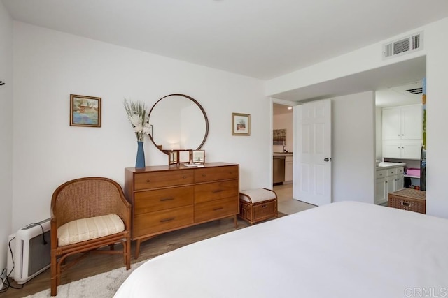 bedroom featuring visible vents, ensuite bath, and wood finished floors
