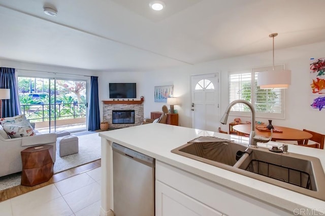 kitchen featuring a sink, a healthy amount of sunlight, light tile patterned flooring, and dishwasher