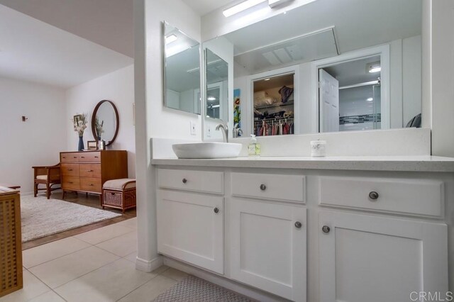 full bathroom with double vanity, tile patterned flooring, a sink, a spacious closet, and a shower with door