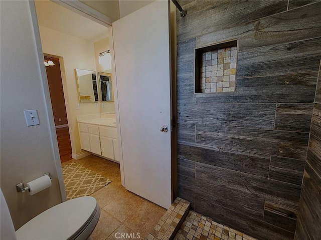 full bath with vanity, toilet, tiled shower, and tile patterned floors