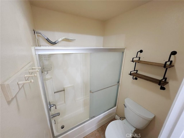 full bathroom featuring a shower with shower door and toilet