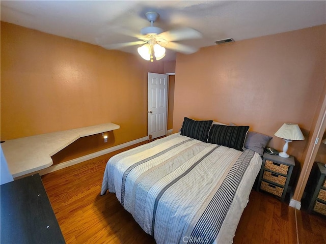 bedroom with ceiling fan, baseboards, visible vents, and wood finished floors