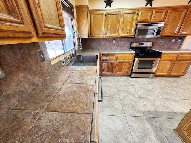 kitchen featuring a sink, stainless steel appliances, backsplash, and tile countertops